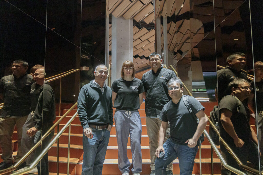 Group of four people standing on a staircase and smiling at the camera